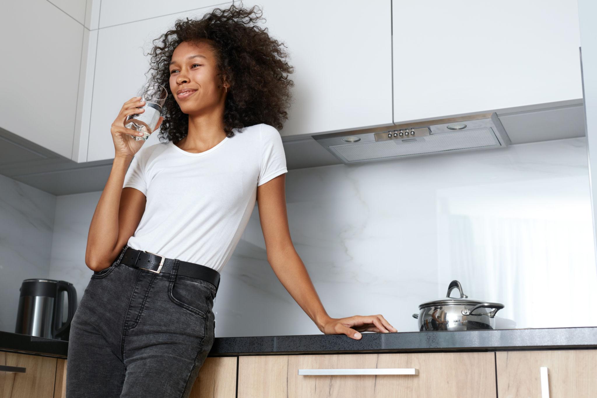 Woman enjoying clean filtered water in her kitchen